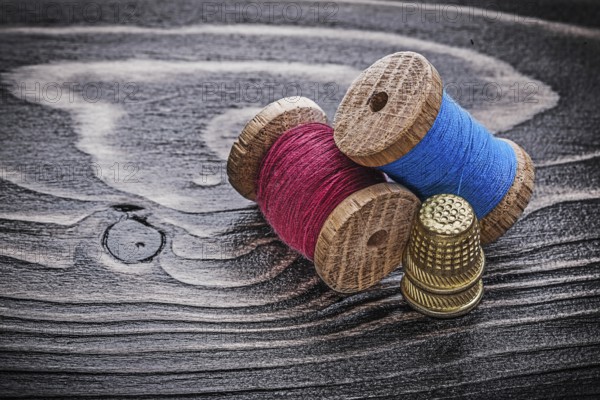 Vintage spools of thread thimbles on wooden board fancy-work concept