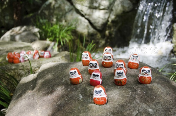 Traditional japanese Daruma dolls in front of a water fall at Katsuo Ji Temple in Mino, Japan, Mino, Japan, Asia