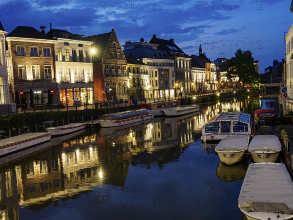 Evening view of the river with illuminated historical buildings and boats, Ghent, Belgium, Europe