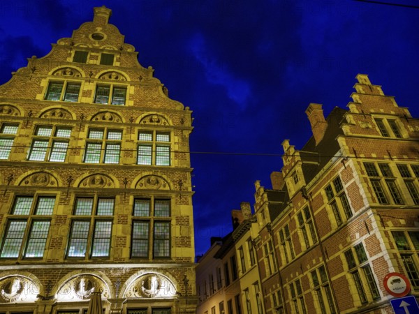 Two illuminated historical buildings at night, glowing in blue light. Cloudy sky, Ghent, Belgium, Europe