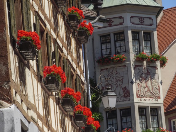 Historic half-timbered house with windows and red flowers under a blue sky, Meersburg, Lake Constance, Germany, Europe