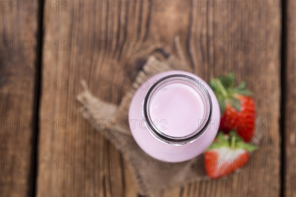 Milk (Strawberry flavoured) on wooden background (selective focus)