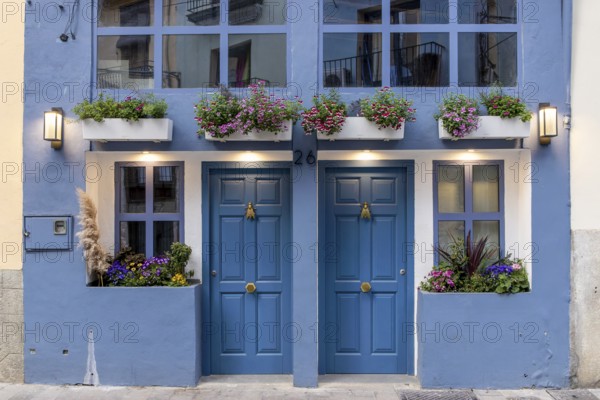 Detail of a building with a blue façade and two symmetrically arranged doors and windows, richly decorated with flowers in the centre of the old town, Valencia, Autonomous Community of Valencia, Province of Valencia, Spain, Europe