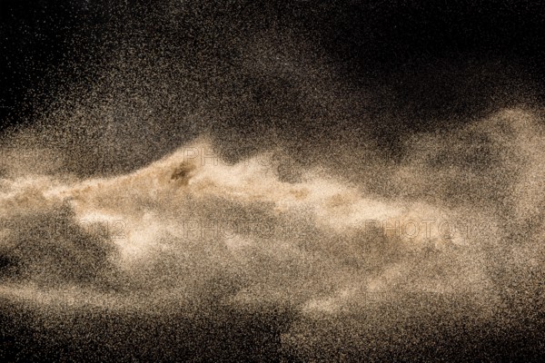 Dry river sand explosion. Golden colored sand splash against black background