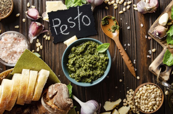 Flat lay view at food background with genovese pesto sauce and its ingredients on wooden kitchen table representing mediterranean cuisine