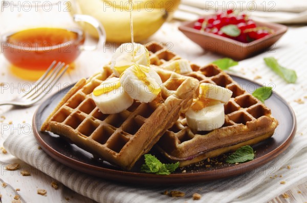 Homemade crispy Belgian waffles served with banana and honey