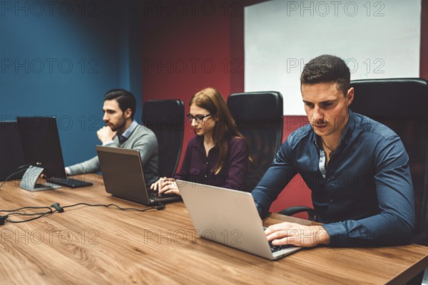 Start up company, young caucasian business people at work, brainstorming ideas, working on computers coding. Colorful offices with young people working in ti