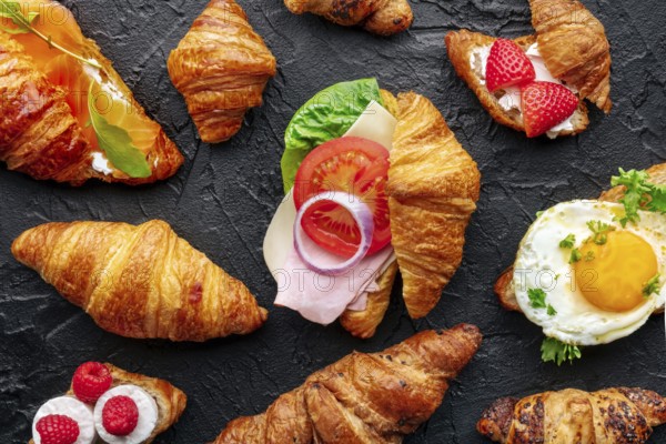 Croissant sandwich assortment. Many stuffed croissants, overhead flat lay shot on a black slate background. Rolls filled with ham, salmon, egg, etc, Food photography, Food photography