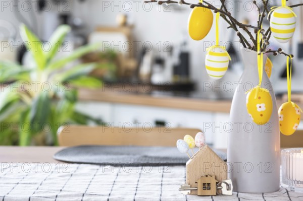 Key to house of cozy home with Easter decor with rabbit and eggs on table of kitchen. Building, design, project, moving to new house, mortgage, insurance, rent and purchase real estate