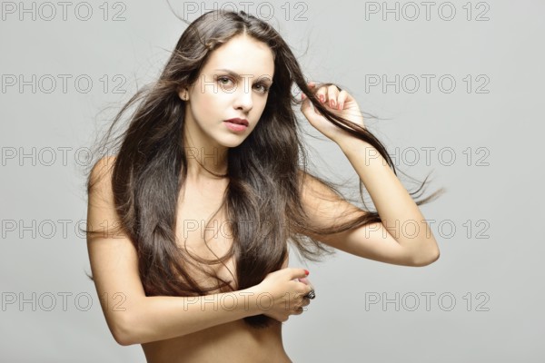 Beautiful naked woman with long hair with naked torso and panties posing in studio