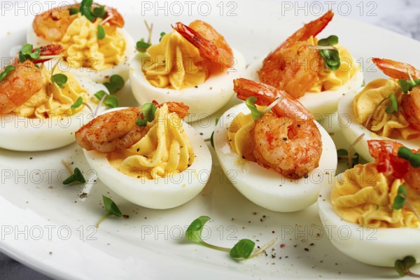 Boiled eggs stuffed with yolk and seasoned with mayonnaise, stuffed eggs with shrimp, on a white plate, selective focus, close-up, without people