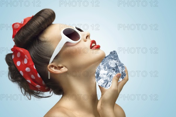 A hot photo of the beauty touching her face with a piece of ice in her hands