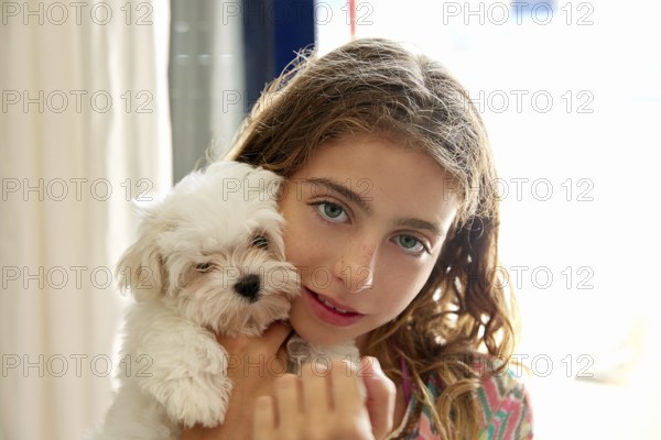 Kid girl with puppy white dog maltichon smiling