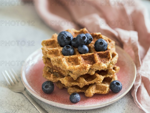 Easy healthy gluten free oat waffles with copy space. Stack of appetizing homemade waffles with oat flour decorated blueberries, on plate over light gray cement background