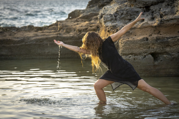 Middle-aged woman dancing and throwing water in the air, Maioris beach, llucmajor, Majorca, Balearic Islands, Spain, Europe