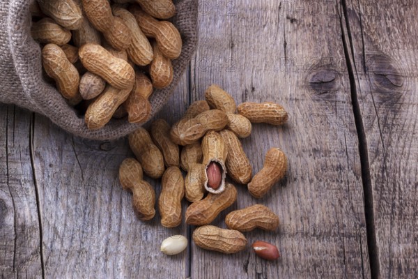 Peanuts in a burlap sack on wooden background