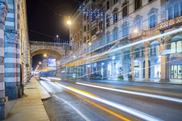 Main Street in Long Exposure with Traffic and Buildings at Night with Light Trails in City of Genoa, Liguria, Italy, Europe