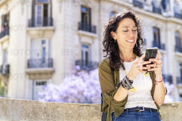 Smiling woman busy on her smartphone against a city backdrop