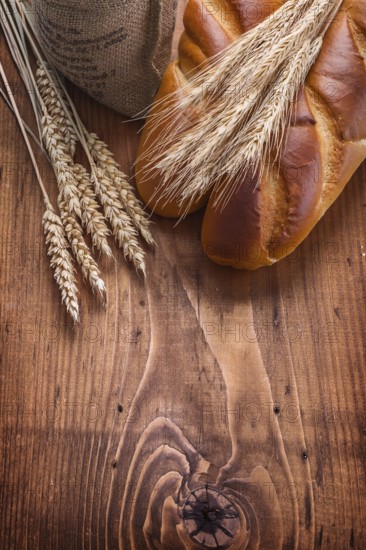 Bguettes and wheat ears on vintage wooden board with copyspace food and drink concept