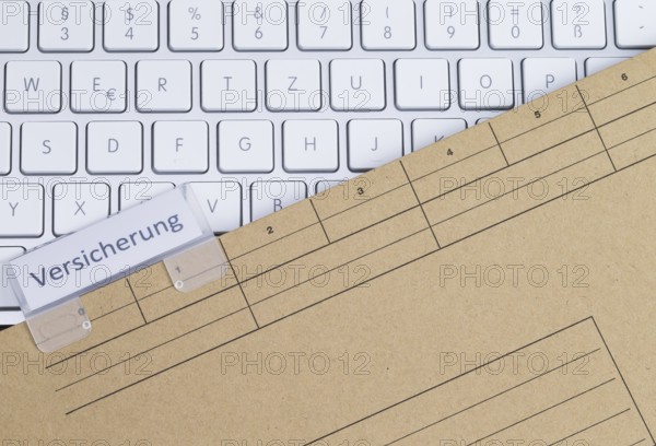 The photo shows a white keyboard with an insurance file folder