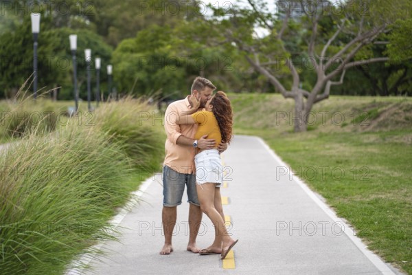 Couple stops for a moment to kiss during their walk through a park