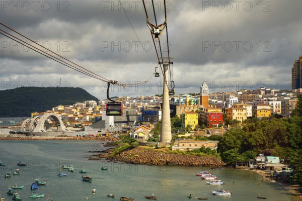 Cable cars over a city with colorful buildings by the waterfront under a cloudy sky, cable car, cable line cub, palms, city, sun city, Phu Quoc, Vietnam, Asia
