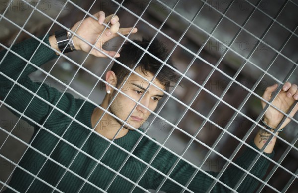 Handsome young man caged behind metal or steel net