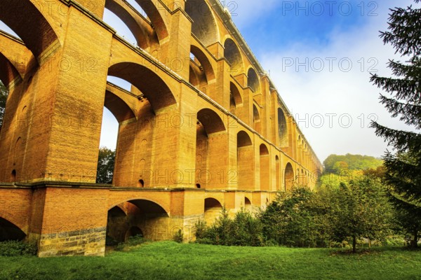 Germany. The Goltzsch Viaduct is the largest red brick viaduct in the world. Sunny cold morning in October. Magnificent huge bridge in a beautiful green park