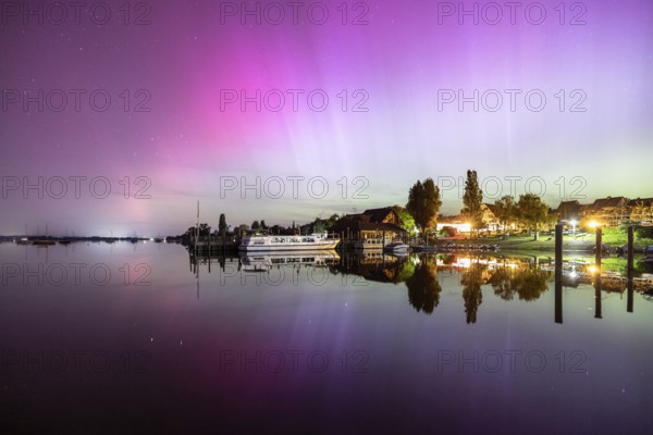 A calm lake at night, surrounded by shining auroras and reflecting houses, harbour, Allensbach, Lake Constance, Baden-Württemberg, Germany, Europe