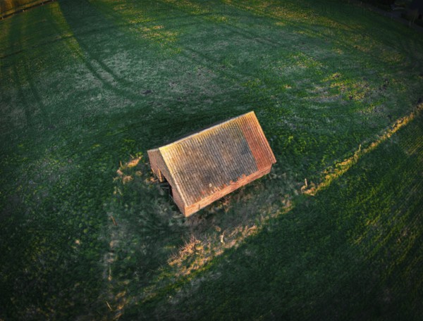 Hut in the evening light on a grass field, aerial view with long shadows at sunset, 27798 Hude-Germany