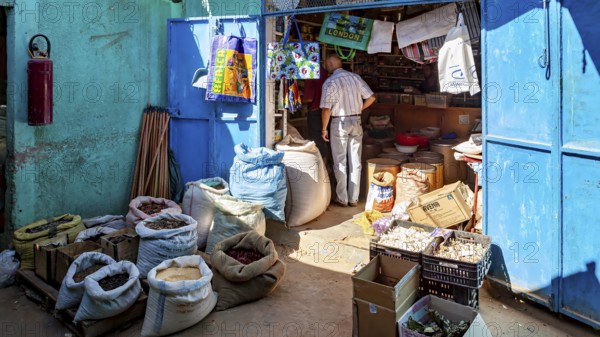 A man in a small shop full of colourful sacks and goods in bright sunshine, Small shop in Tamanrasset in the Sahara in Algeria
