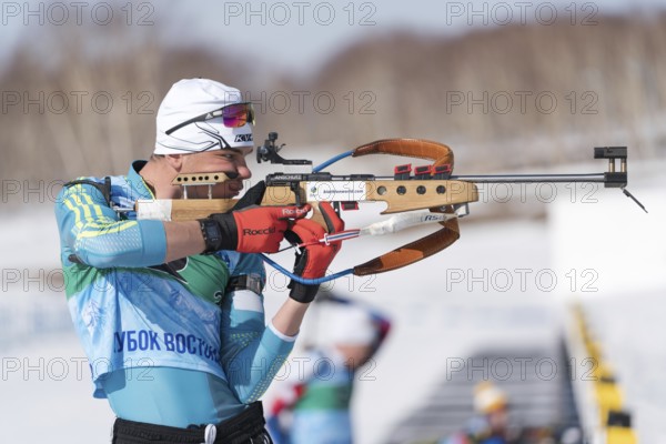 Sportsman biathlete aiming rifle shooting in standing position. Kazakhstan biathlete Kireyev Vladislav in shooting range Junior biathlon competitions East of Cup. Kamchatka, Russia, April 14, 2019, Europe