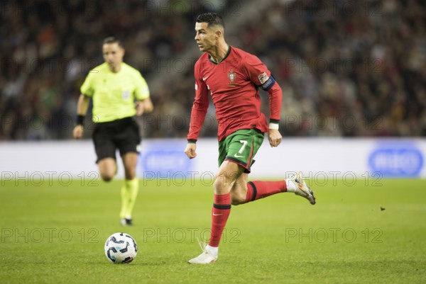 Football match, captain Cristiano RONALDO CR7 Portugal on the ball running towards the left looking forwards, captain's armband, referee Donatas RUMSAS Lithuania trying to keep an eye on the action, sequence 4, Estadio do Dragao, Porto, Portugal, Europe