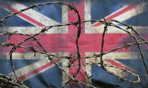 Barbed wire in front of an old stained dirty union jack british flag with dark crumpled edges brexit freedom of movement isolationist concept