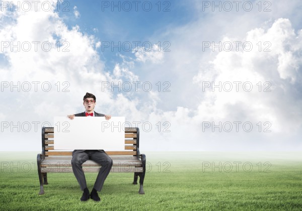 Young businessman sits on a wooden bench with an empty banner
