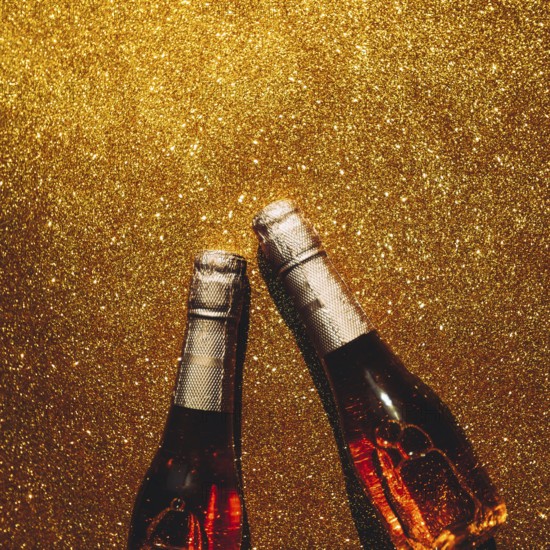 Christmas or New Year composition with bottles of rose champagne on golden shiny background, top view with dark shadows. Celebration flat lay. Party creative concept
