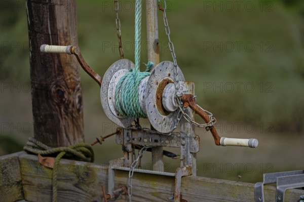 A close-up of an old, rusted winch with green rope attached, mounted on wooden pillars, the practice of fishing in fish ditches is a traditional activity that is disappearing, Mornac-sur-Seudre, Charente-Maritime, France, Europe