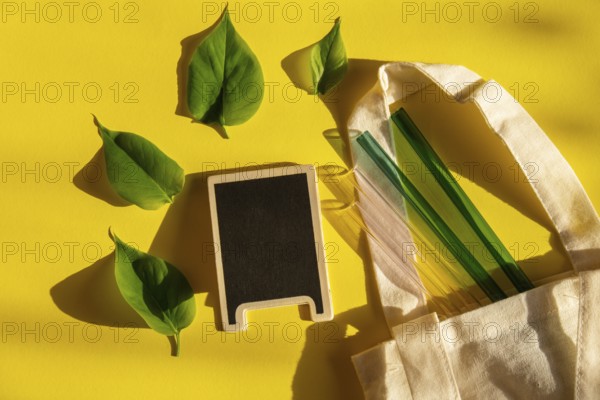 Reusable glass Straws on colorful background with green leafs in eco bag Eco-Friendly. Empty blackboard mock up template for copy space text. Drinking Straw Set Reusable Comfortable Rounded tip Drinking Straw. Zero waste, plastic free concept. Sustainable lifestyle. Picnic concept