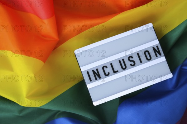 Rainbow flag with lightbox and text INCLUSION. Rainbow lgbtq flag made from silk material. Symbol of LGBTQ pride month. Equal rights. Peace and freedom. Support LGBTQ community