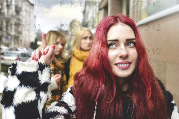 Self-confident teenage girl ignores jealous people who spread gossip behind her back. stop bullying. social problems. a girl shows her middle finger to her detractors