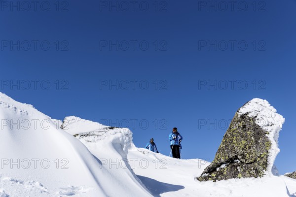Sofia, Bulgaria - March 12, 2016: Two free riders are prepairing for skiing down a snowy rocky mountain top. During a bright sunny day. Clear blue sky