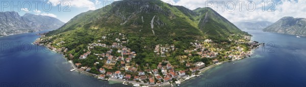 Old houses with red roofs on the seashore on the slope of a green mountain. Montenegro. Drone. Panorama., Kotor Municipality, Montenegro, Europe