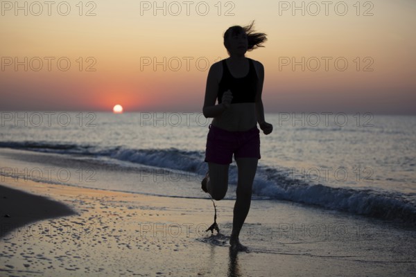 Silhouette of a sportswoman against the background of a sunrise by the sea