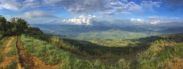 Panorama over the cliffs into a green valley and mountains in sun and shadow, blue sky and white clouds Barichara, Colombia, South America