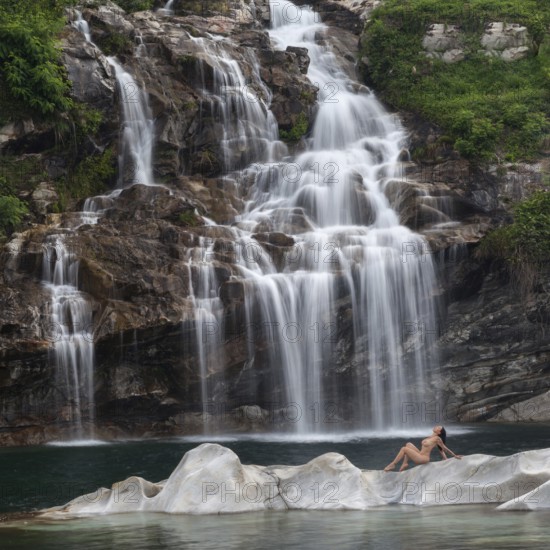Professional model in elegant pose on a rocky island in front of an impressive waterfall, Aesthetic Nude Photography Outdoor Shooting, Maggia, Maggia Valley Canton Ticino, Switzerland, Europe