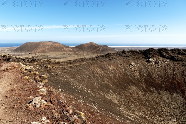 Impressive volcanic landscape with dry craters and vast skies in a natural setting. Beautiful volcanic landscape of the crater of the Calderón Hondo volcano with hiking trail. La Olivia, Fuerteventura. Spain