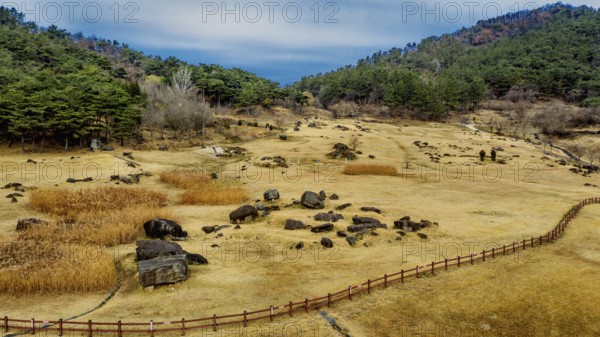 Gochang, South Korea. Dec. 4, 2024. Aerial view of dolmen tomb site with mountains and blue cloudy sky in background