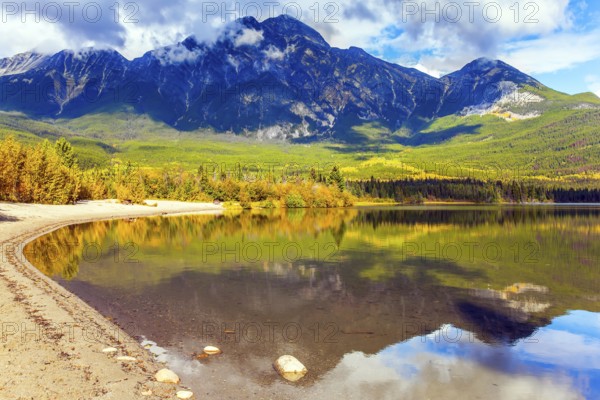 Rocky Mountains of Canada. Smooth water of the lake reflects Pyramid Mountain and lush cumulus clouds. Pyramid Lake. Active eco and photo tourism concept