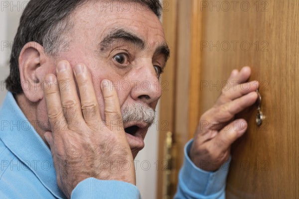 Senior man looking through peephole