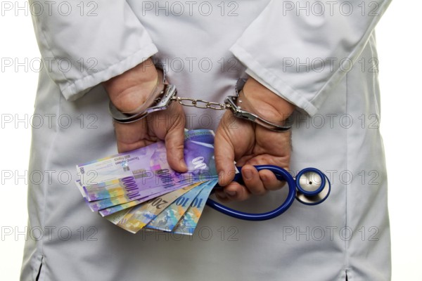 A doctor with Swiss franc banknotes and handcuffs, Austria, Europe